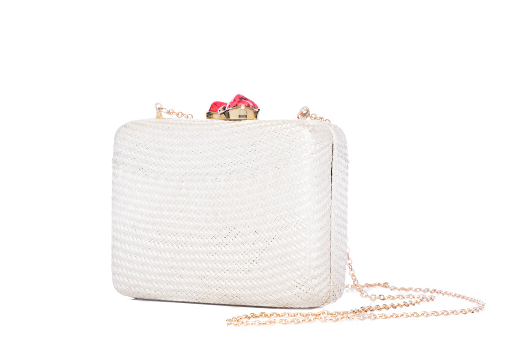 Iris White Woven Clutch made from sustainable plant fibers, featuring a bold red stone accent, brass drop-in chain strap, and fully lined interior for an eco-friendly yet elegant look.