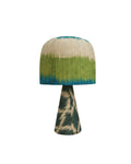 Front view of a green and blue ikat pattern dome table lamp with a patterned conical base against a white background.