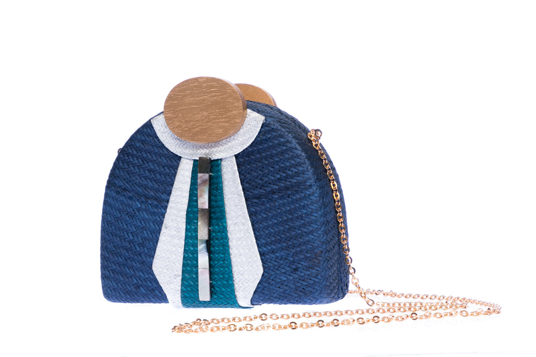 Gatsby Navy half-moon clutch made from handwoven natural plant fibers with a cracked sea shell bar and a brass chain strap, offering elegance and sophistication for evening events.
