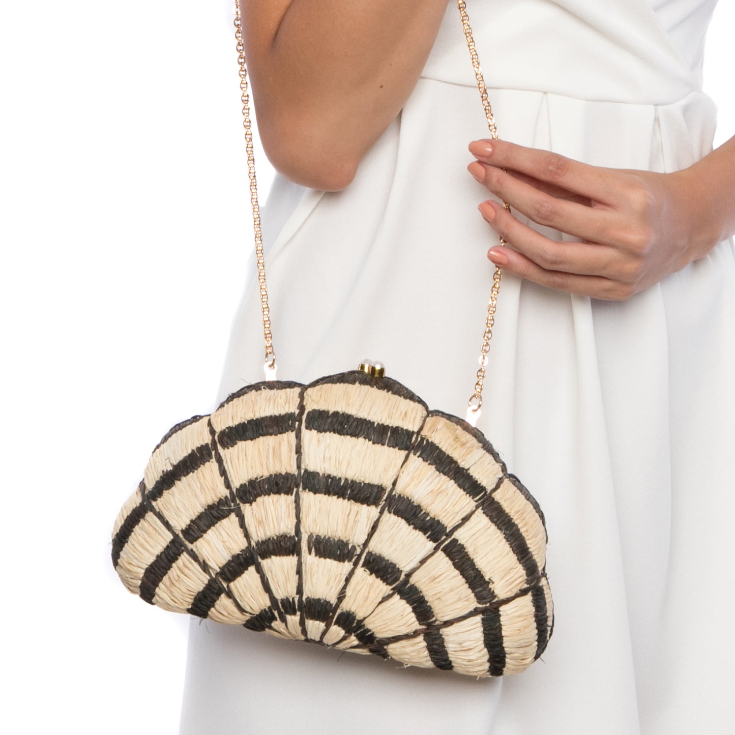 Seashell Karuna Clutch featuring hand-embroidered raffia fiber, freshwater pearls wrapped in brass, and a brass drop-in chain strap for versatility.