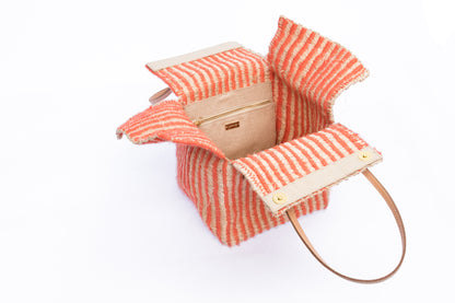 Pumpkin-colored Dolly Cube Handbag, handwoven with natural plant fibers and acrylic yarn, featuring sturdy cow leather handles and magnetic closures.
