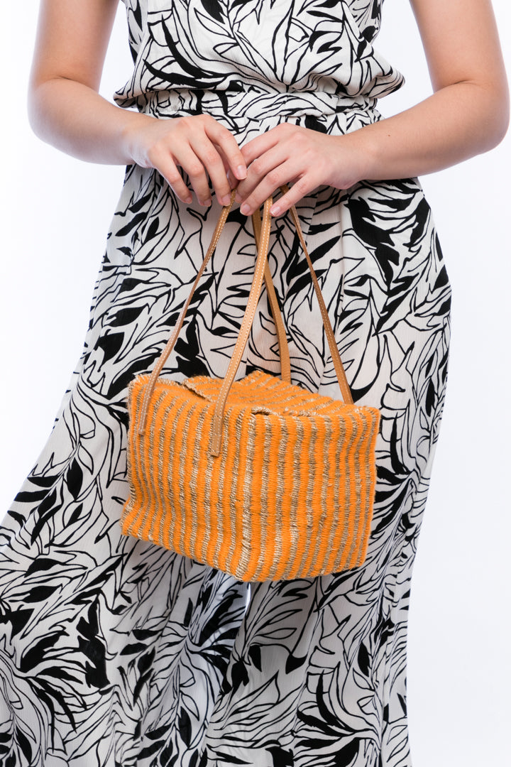 Pumpkin-colored Dolly Cube Handbag, handwoven with natural plant fibers and acrylic yarn, featuring sturdy cow leather handles and magnetic closures.