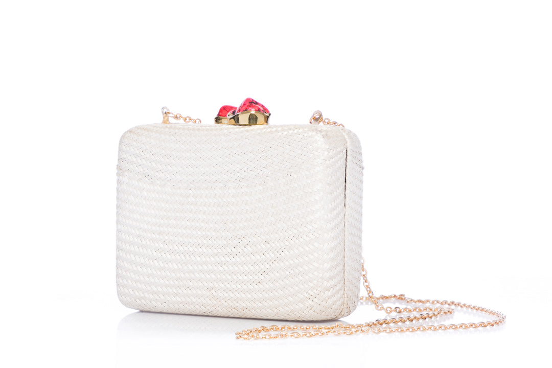 Iris White Woven Clutch made from sustainable plant fibers, featuring a bold red stone accent, brass drop-in chain strap, and fully lined interior for an eco-friendly yet elegant look.